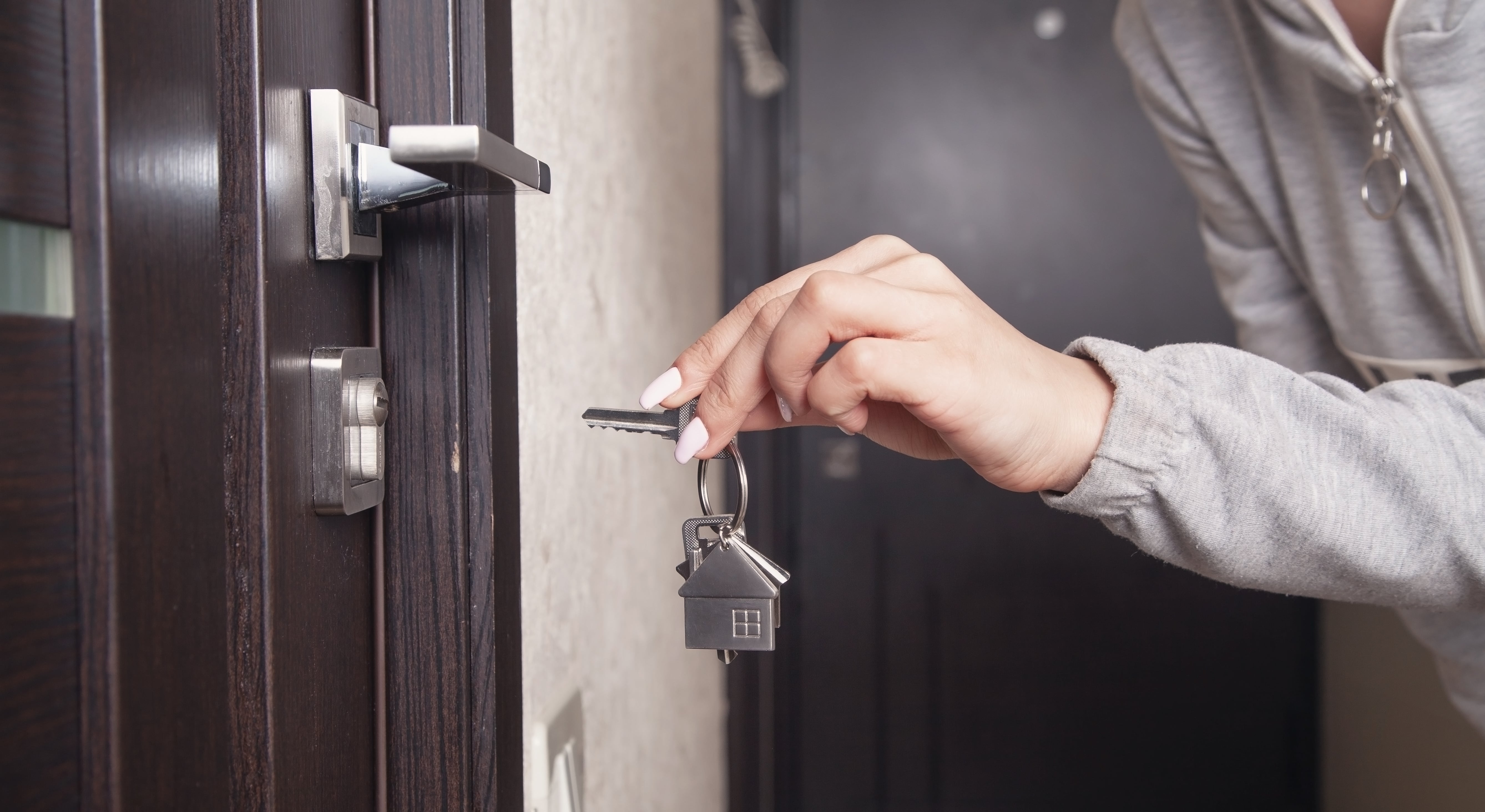 A key with a house-shaped keychain about to unlock a door lock